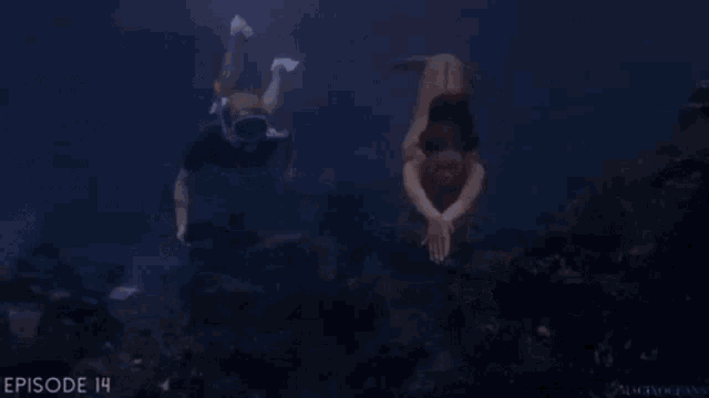 a man and a mermaid are swimming underwater and the man is holding the mermaid 's hand .