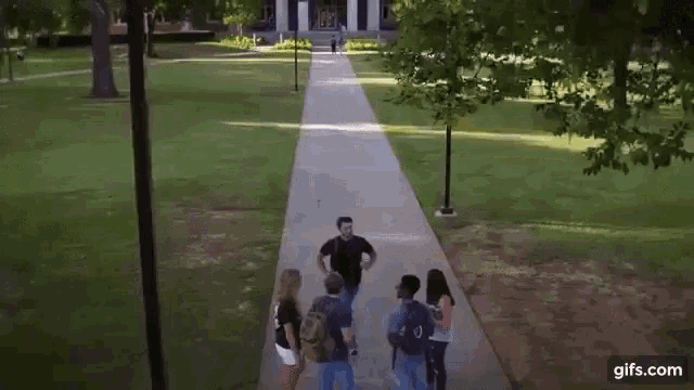 a group of students are walking down a sidewalk .