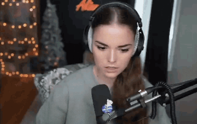 a woman wearing headphones stands in front of a microphone