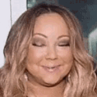 a close up of a woman 's face with her eyes closed smiling .