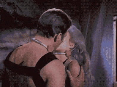 a man and a woman are kissing each other in a room .