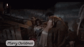 a man is kneeling down next to a woman in a nativity scene with a merry christmas message .