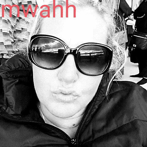 a woman wearing sunglasses and a black jacket with the word mwahh in red