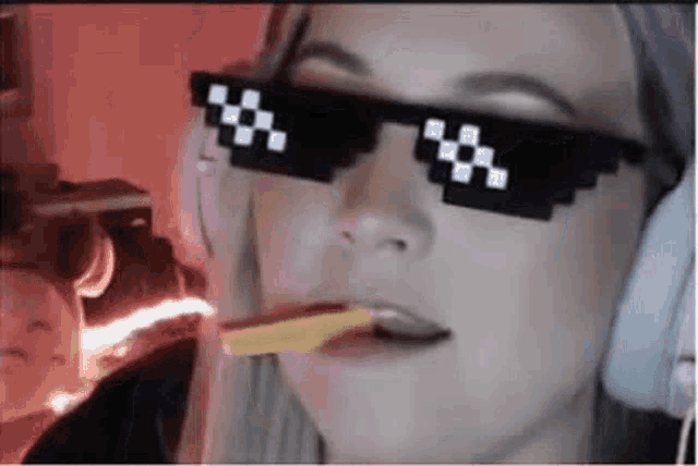 a woman wearing pixelated sunglasses and headphones is eating a piece of pizza .
