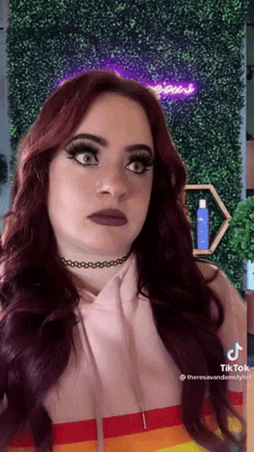 a woman with red hair is wearing a pink hoodie and a rainbow shirt