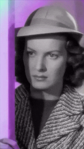 a black and white photo of a woman wearing a hat and coat