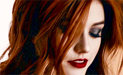 a close up of a woman with red hair and red lipstick