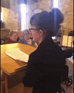 a woman in a wheelchair is singing in front of a group of older women