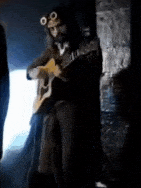 a man is playing an acoustic guitar in a dark room .