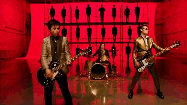 a group of men playing guitars in front of a red wall