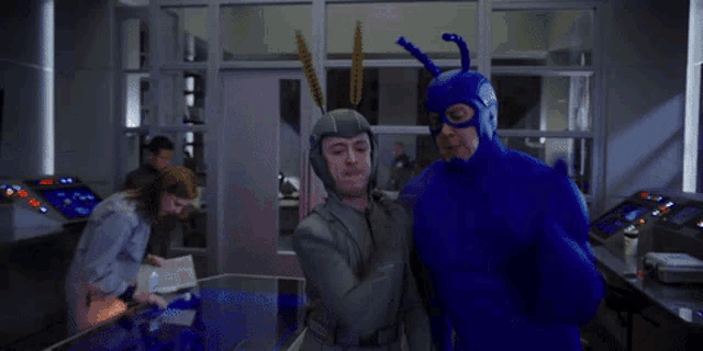 a man in a blue superhero costume stands next to another man