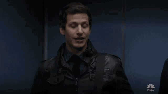 a man in a leather jacket is standing in front of a sign that says cool