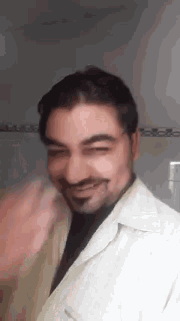 a man with a beard and mustache is smiling and waving his hand .