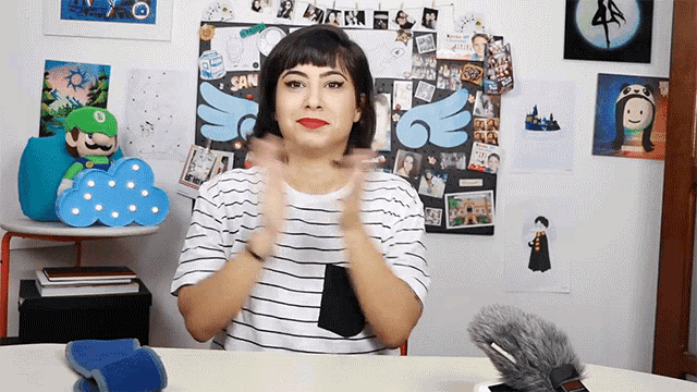 a woman applauds in front of a wall that has a collage of pictures on it that says san