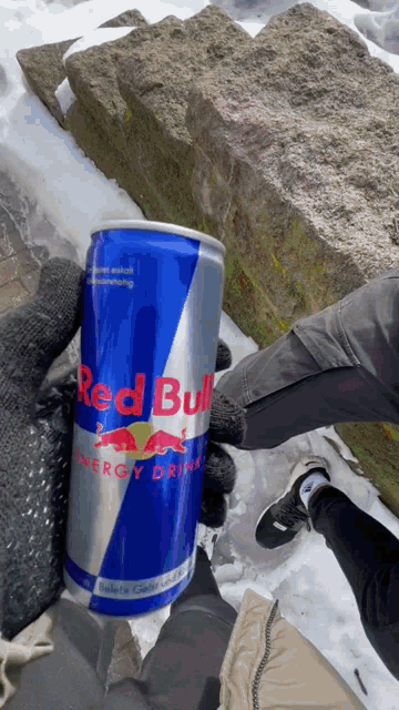 a person holding a can of red bull in their hand