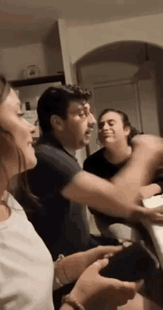 a group of people are sitting around a table playing a video game and laughing .