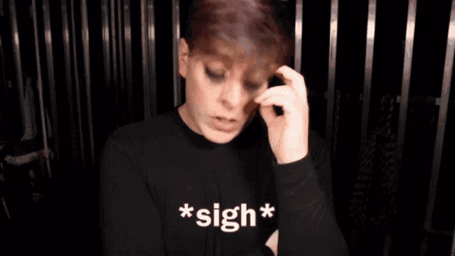 a young man wearing a black shirt that says sigh