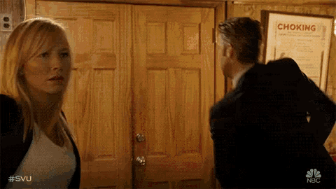 a man and a woman are standing in front of a wooden door in a room .