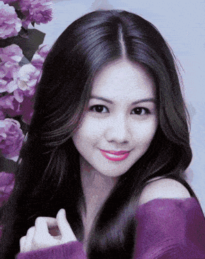 a woman with purple flowers in the background is smiling