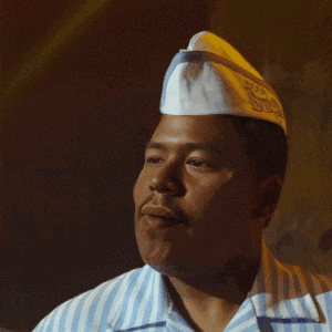 a man wearing a white hat and a blue and white striped shirt smiles