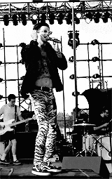 a man in zebra print pants is singing into a microphone on a stage