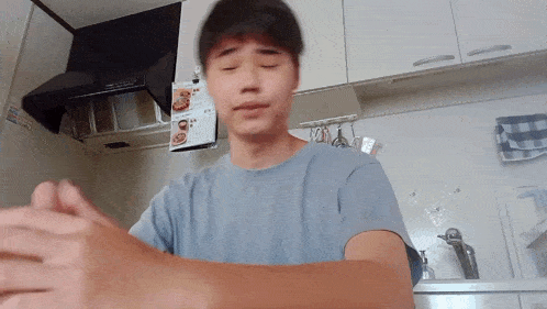 a man in a blue shirt is standing in a kitchen