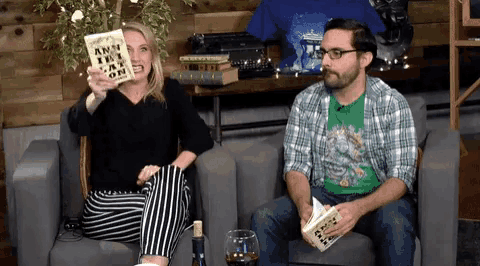 a man and a woman are sitting on a couch reading a book called ain 't it a wonderful life