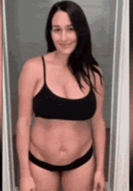 a woman in a black bra and underwear is standing in front of a mirror .