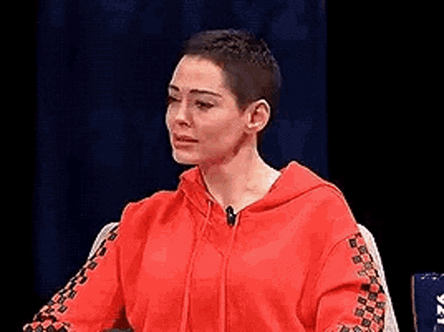 a woman in a red hoodie is sitting in front of a microphone .