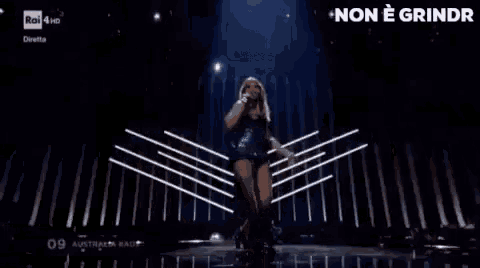 a woman is singing into a microphone on stage .