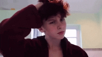 a young girl is holding her hair in a bun while wearing a red robe .