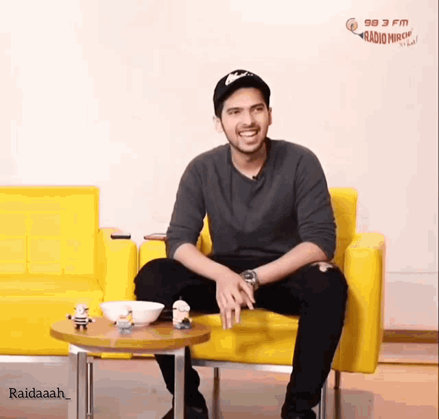 a man sitting on a yellow couch with a sign that says 98.7 fm radio music