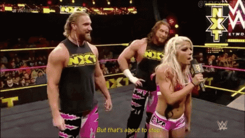 a woman is talking into a microphone in a wrestling ring while two men stand behind her ..