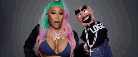 a woman with pink and green hair is standing next to a puppet wearing a black shirt that says logo .