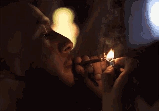 a man is smoking a cigarette with a lighter