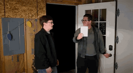 two men are standing in front of a door with knauf insulation on the wall