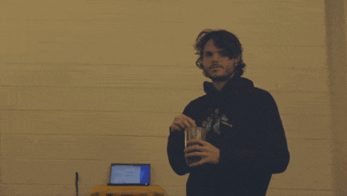a man wearing a hoodie that says ' nirvana ' on it is holding a glass