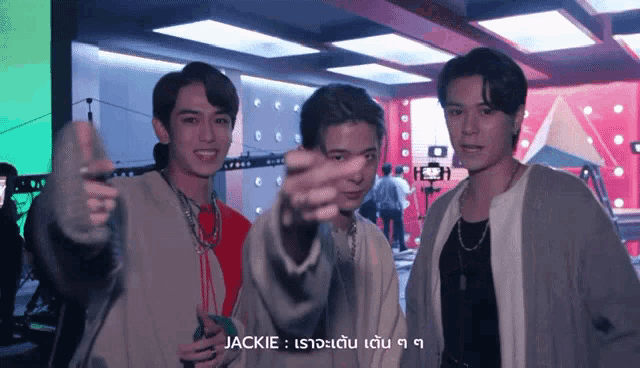 three young men are standing next to each other and one of them is pointing at the camera