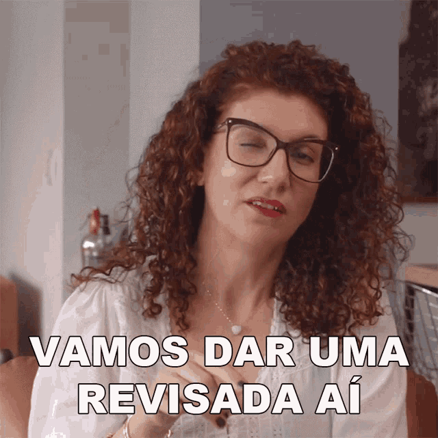 a woman with curly hair wearing glasses and a white shirt says vamos dar uma revisada ai