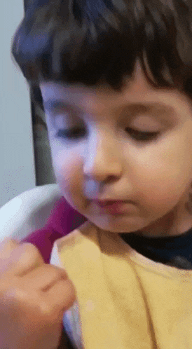 a close up of a child 's face with a yellow bib