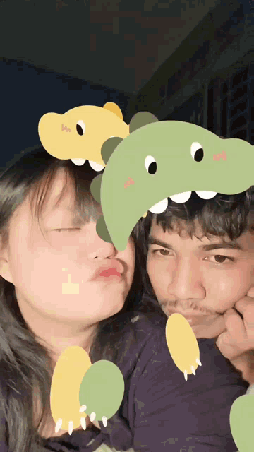 a man and a woman are posing for a picture with a dinosaur on their face