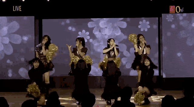 a group of girls are performing in front of a large screen that says live