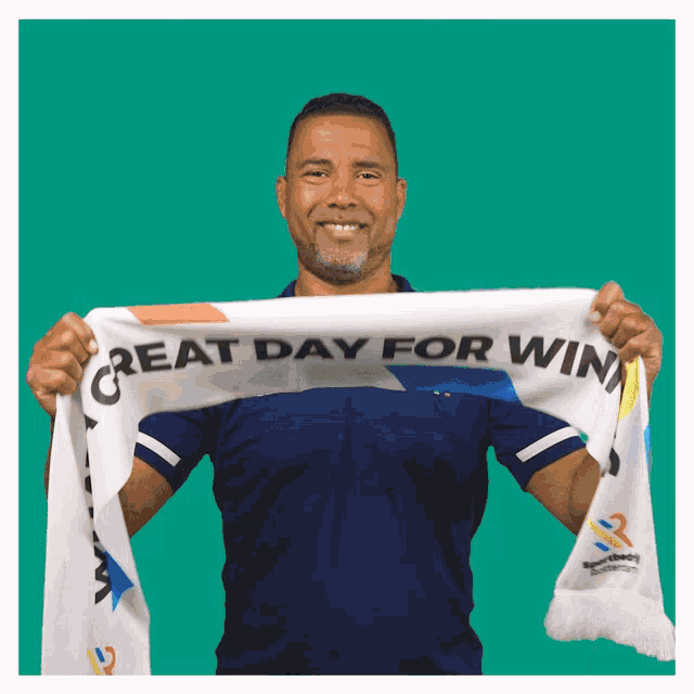 a man in a blue shirt holds a scarf that says great day for win