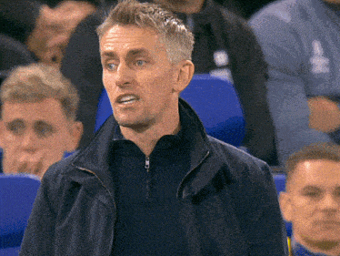a man wearing a blue jacket stands in a crowd