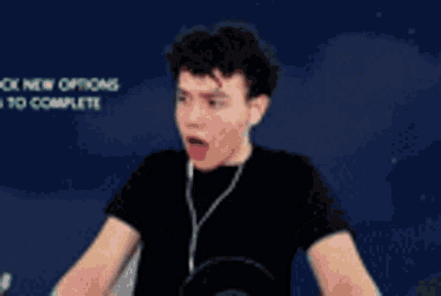 a young man wearing headphones is making a funny face while sitting in front of a microphone .