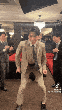 a man in a suit and tie is dancing in front of a group of men