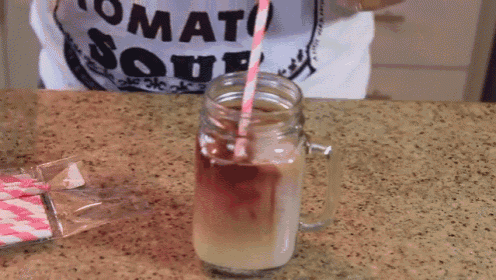 a person wearing a tomato soup shirt is pouring a drink into a mason jar with a pink straw
