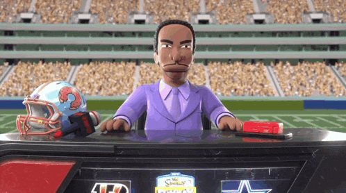 a man in a purple suit sits at a desk with a football helmet on it and a sign that says td