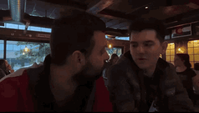 two men kissing in a restaurant with a sign that says ' denver ' on it