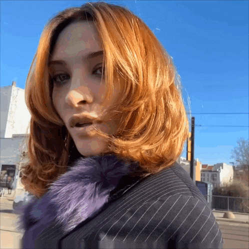 a woman with red hair is wearing a purple fur collar